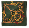 A square silk scarf featuring an intricate equestrian theme print. The design showcases golden horse bits and reins intertwined with brown leather straps and red tassels, all set against a dark forest green background.