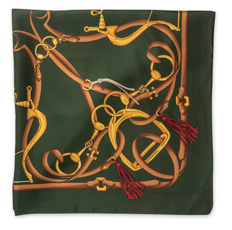 A square silk scarf featuring an intricate equestrian theme print. The design showcases golden horse bits and reins intertwined with brown leather straps and red tassels, all set against a dark forest green background.