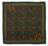 A square silk scarf featuring an intricate paisley pattern in dark green, rust red, and gold, with decorative bird motifs in the corners, shown flat against a white background.